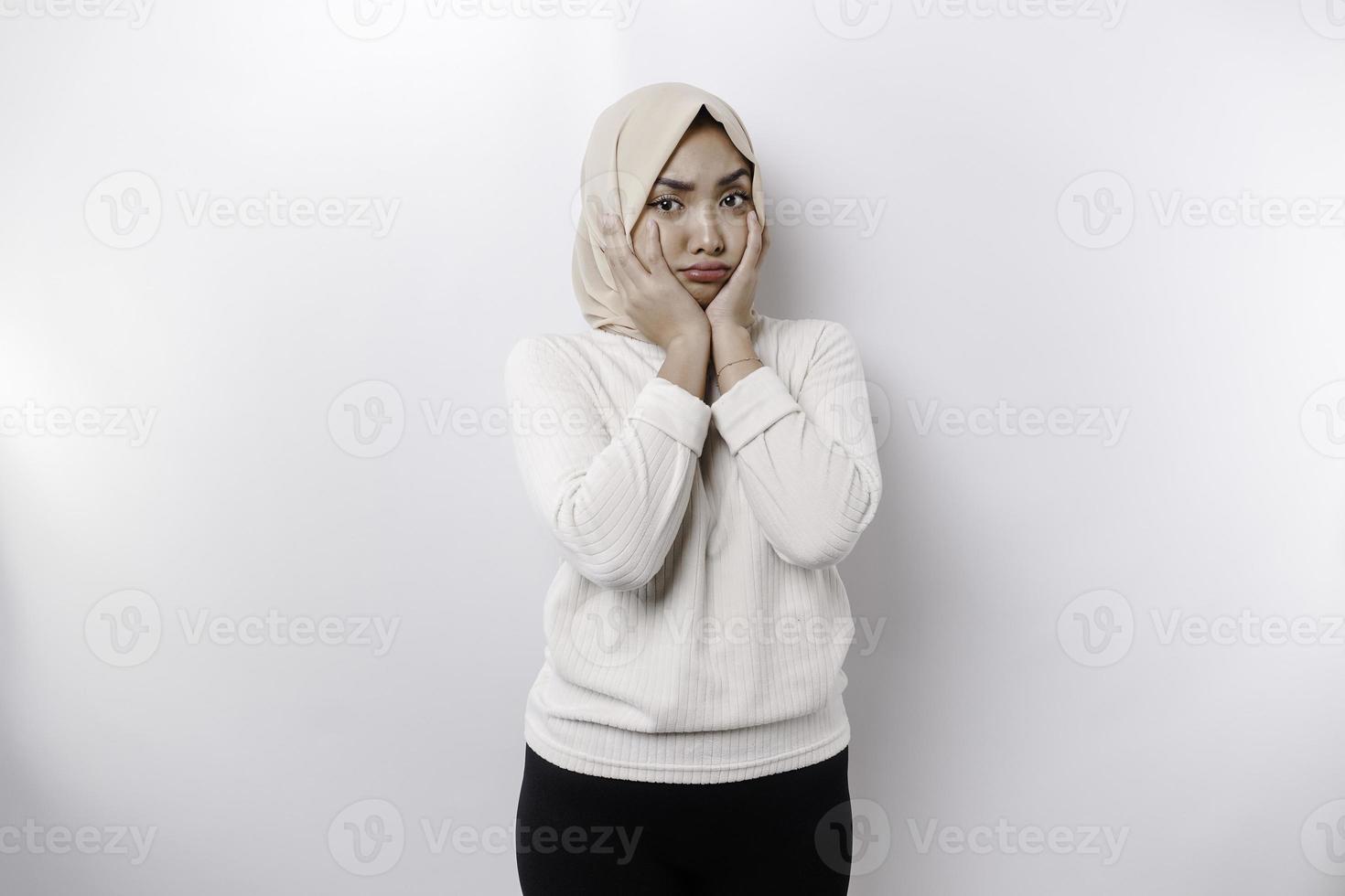 A portrait of a cute Asian Muslim woman wearing a headscarf, and feeling excited and isolated by a white background photo