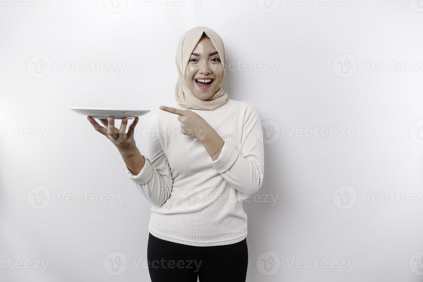 un sonriente asiático musulmán mujer es rápido y hambriento y participación y señalando a un plato foto