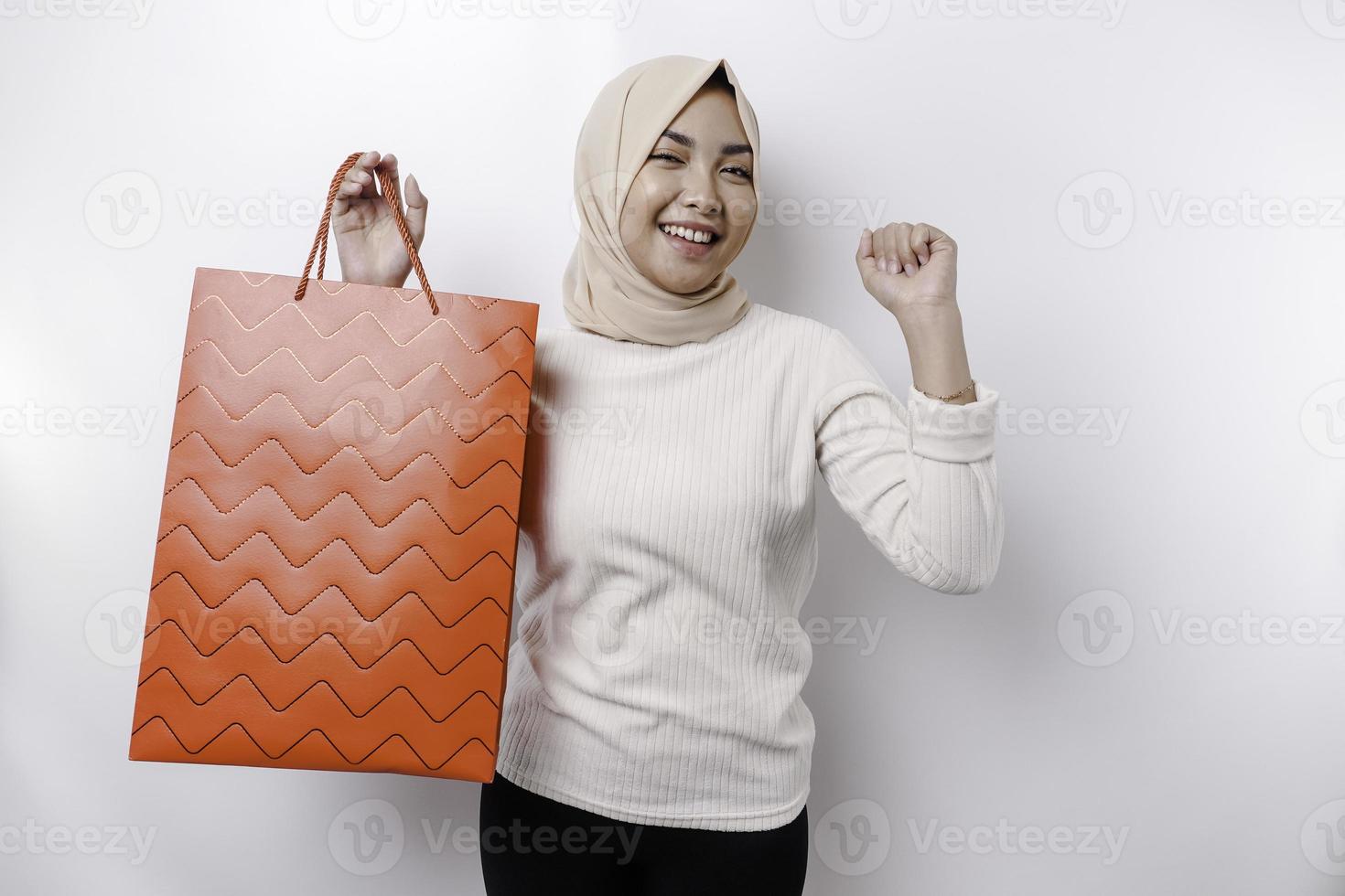 Asian Muslim woman happy beautiful young standing excited holding a shopping bag, studio shot isolated on white background photo