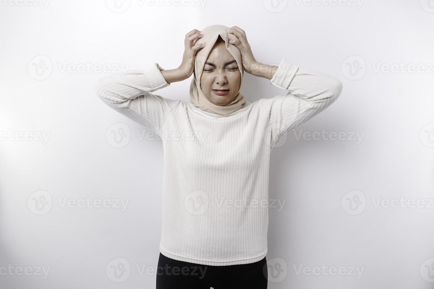 A portrait of an Asian Muslim woman wearing a headscarf isolated by white background looks depressed photo