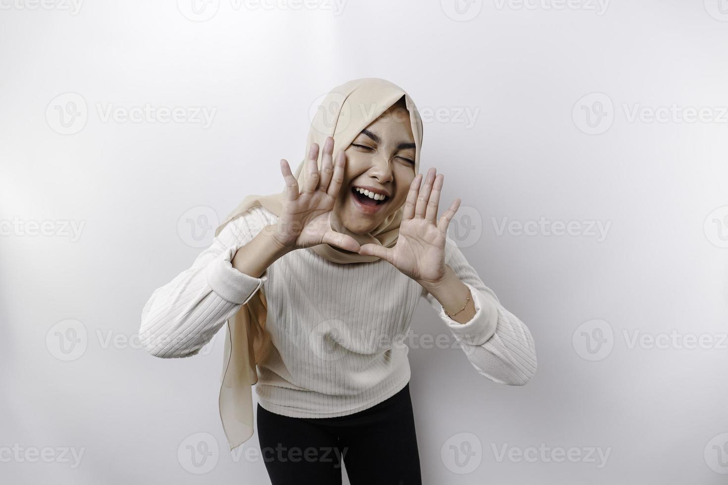 joven hermosa asiático musulmán mujer vistiendo un Pañuelo gritos y gritando ruidoso con un mano en su boca. comunicación concepto. foto