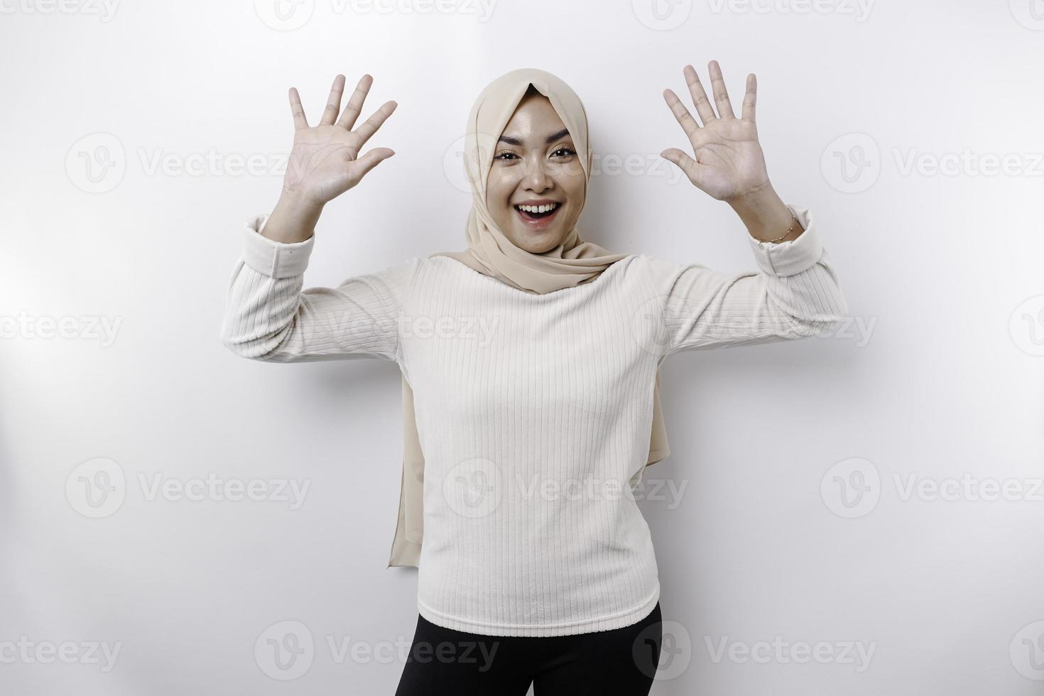 Portrait of a young beautiful Asian Muslim woman wearing a headscarf gesturing Eid Mubarak greeting photo