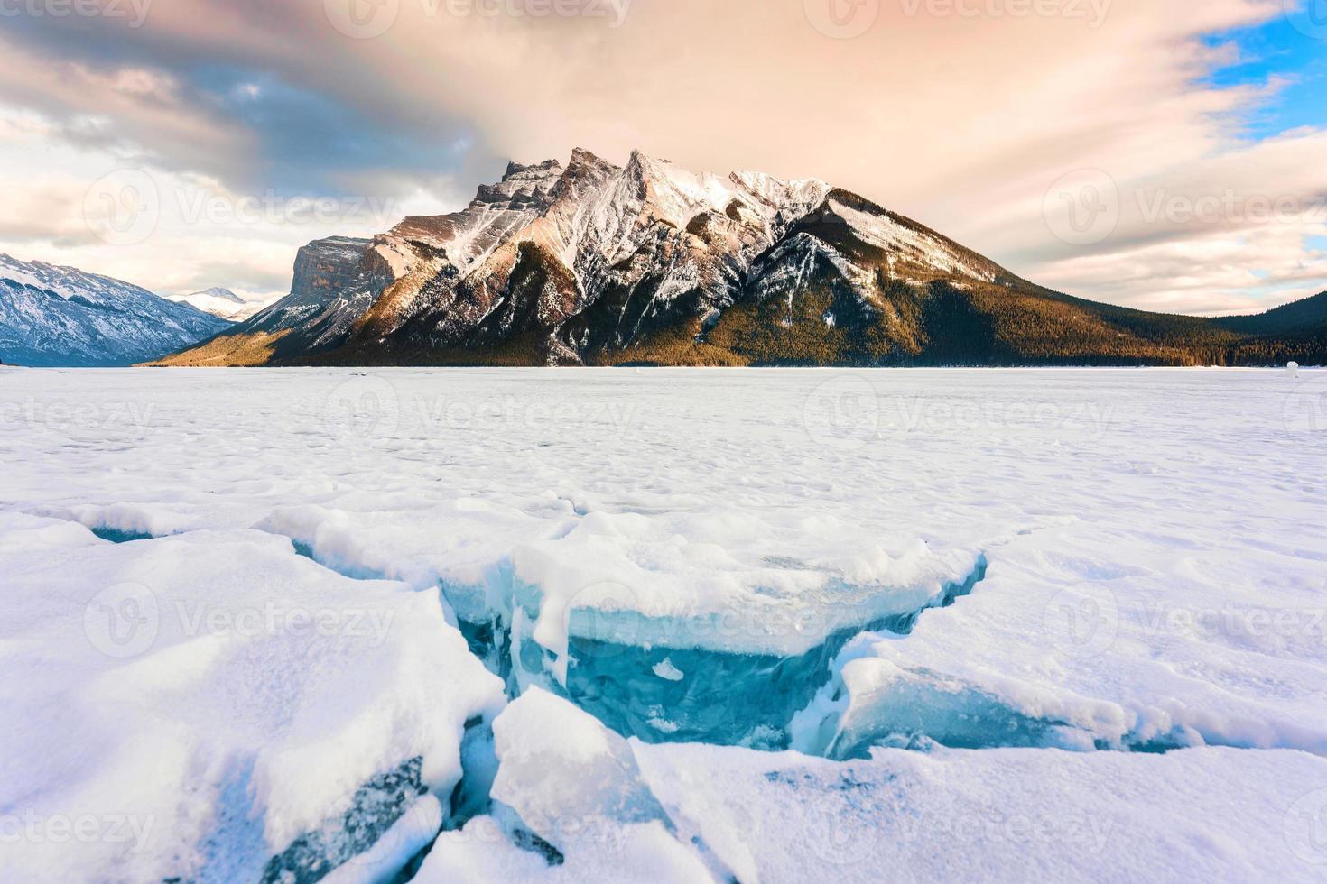 Frozen Lake Minnewanka with rocky mountains and cracked ice from the lake in winter at Banff national park photo