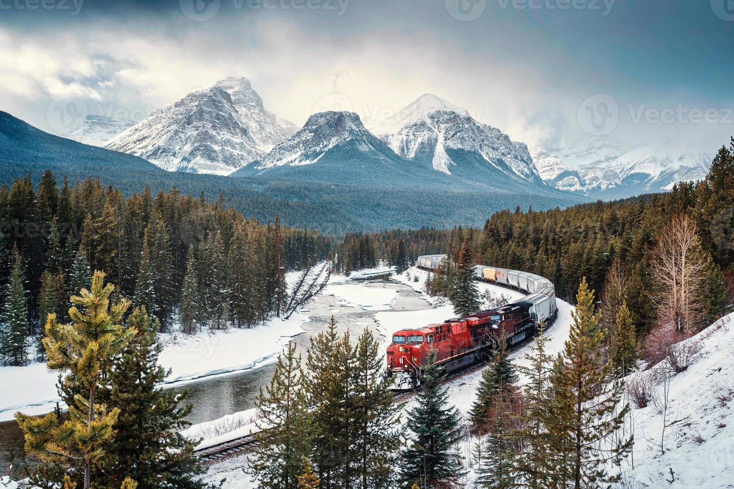 Morants Curve with iconic red cargo train passing through bow valley and rocky mountains in winter at Banff national park photo