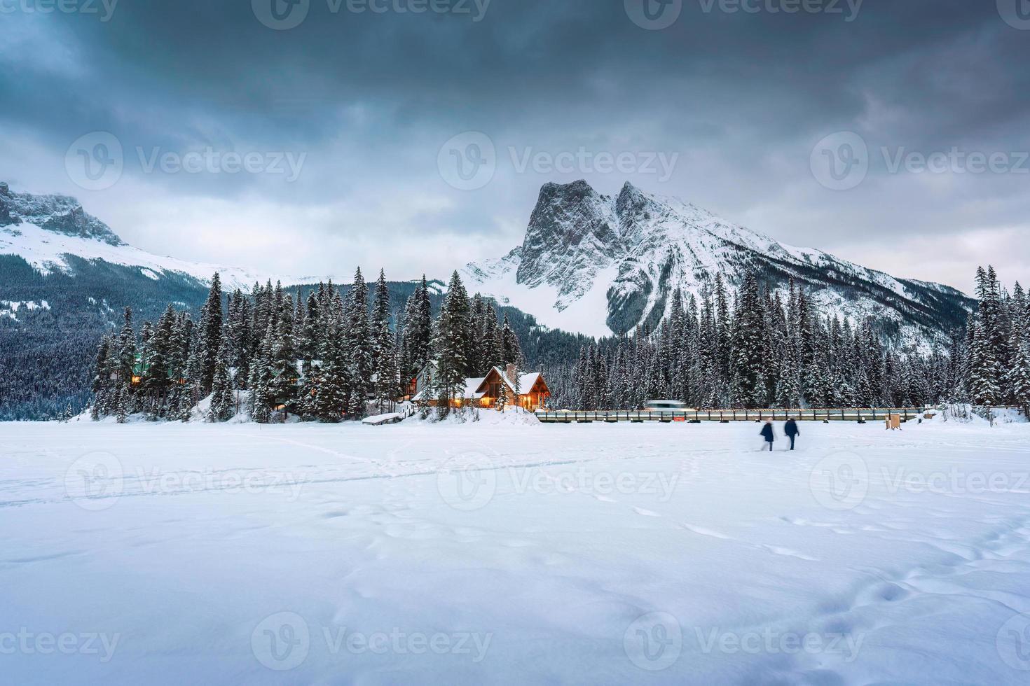Emerald Lake with wooden lodge glowing in snowy pine forest and rocky mountains on winter at Yoho national park photo