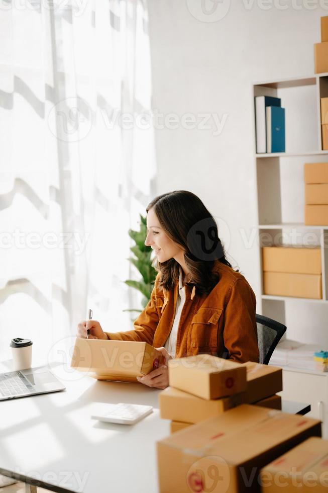 pequeño negocio empresario SME Lanza libre mujer trabajando a oficina, caja, tableta y ordenador portátil en línea, marketing, embalaje, entrega, comercio electrónico concepto foto