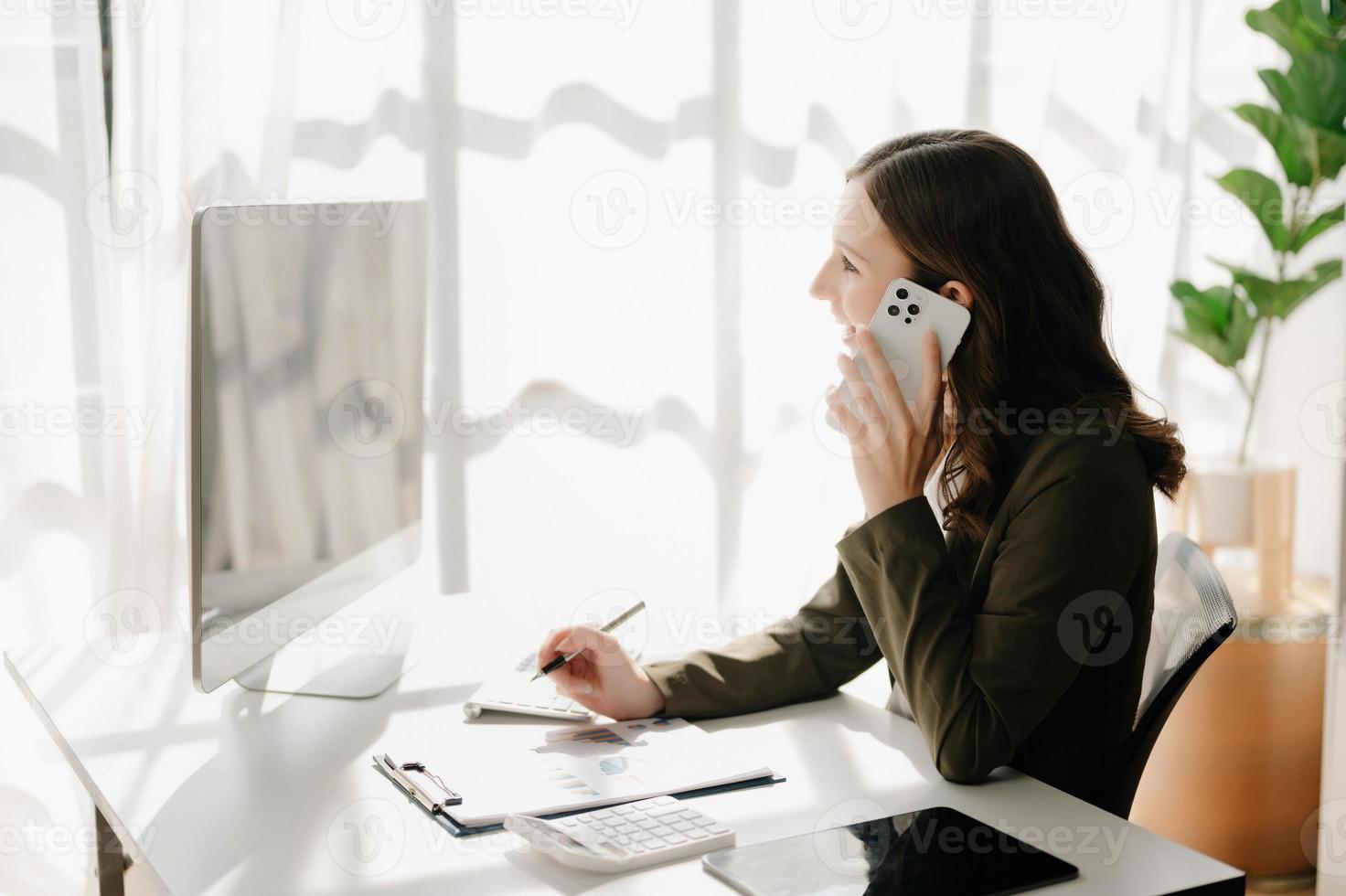 Confident business expert attractive smiling young woman typing laptop ang holding digital tablet  on desk in creative home office. photo