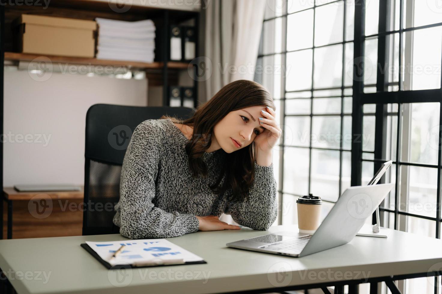 mujer sensación migraña cabeza tensión.con exceso de trabajo mujer de negocios financiero mientras trabajando en ordenador portátil y tableta a oficina. foto