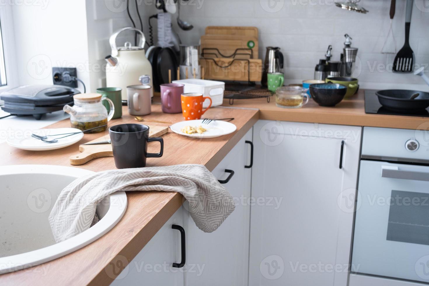 un lío en el cocina, sucio platos en el mesa, dispersado cosas, antihigiénico condiciones. el lavavajillas es lleno, el cocina es desordenado, todos los días vida foto