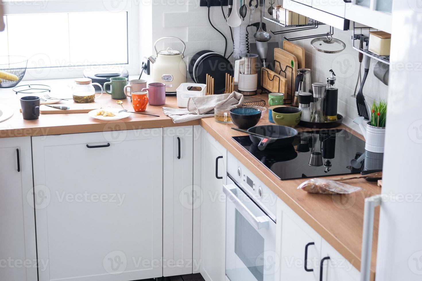 A mess in the kitchen, dirty dishes on the table, scattered things, unsanitary conditions. The dishwasher is full, the kitchen is untidy, everyday life photo