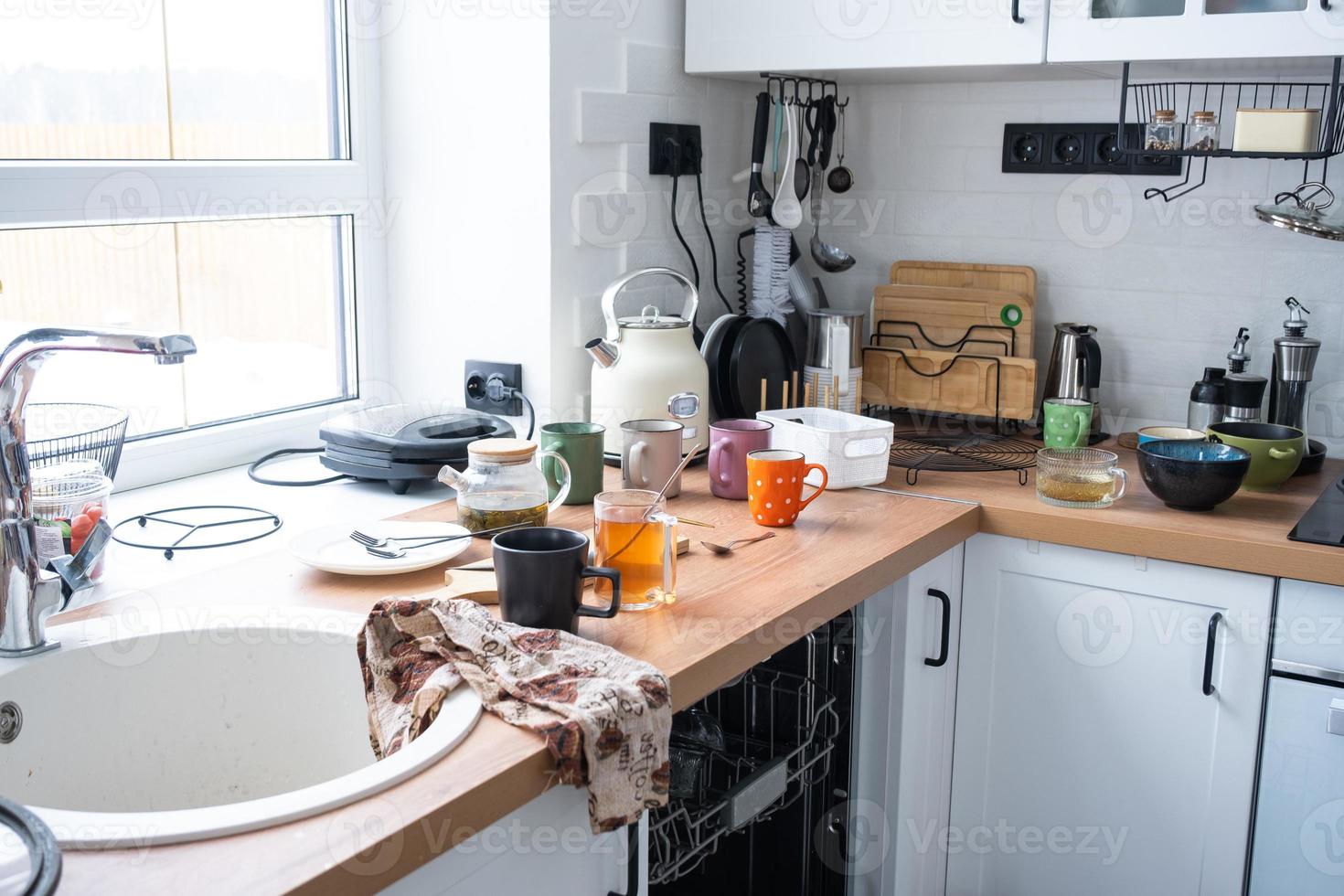 A mess in the kitchen, dirty dishes on the table, scattered things, unsanitary conditions. The dishwasher is full, the kitchen is untidy, everyday life photo