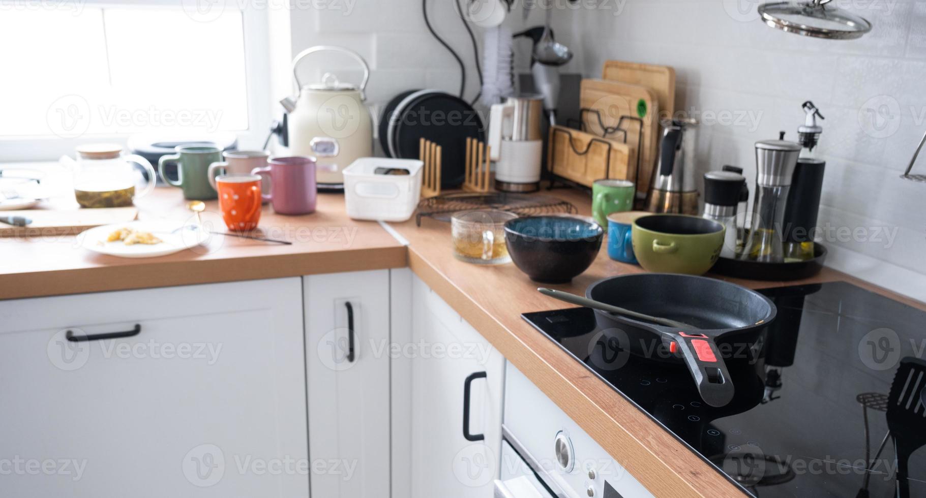 A mess in the kitchen, dirty dishes on the table, scattered things, unsanitary conditions. The dishwasher is full, the kitchen is untidy, everyday life photo