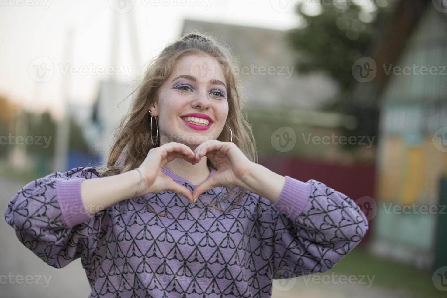 contento joven niña muestra corazón firmar con dedos. foto