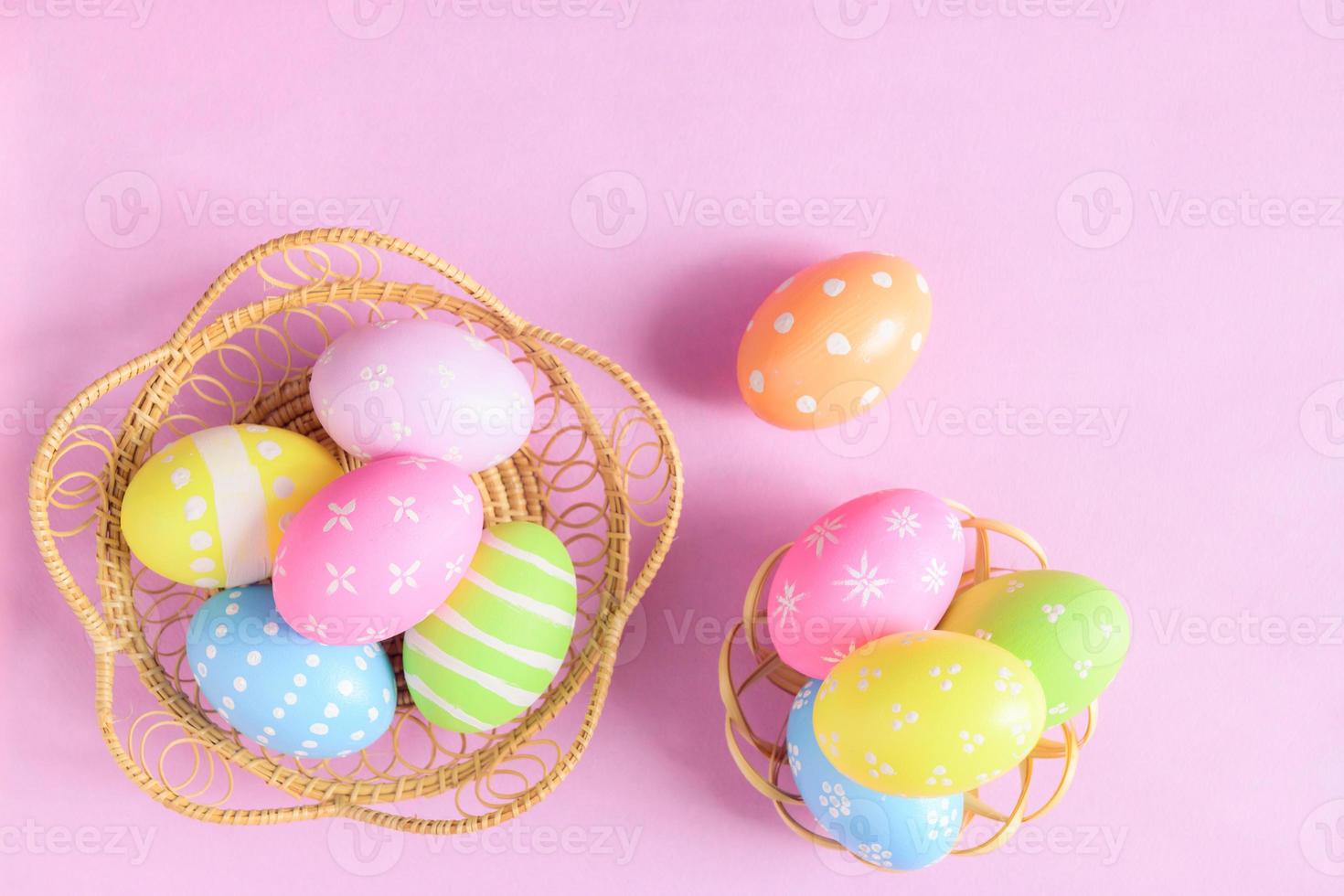 Happy Easter holiday greeting card concept. Colorful Easter Eggs and spring flowers on pastel pink background. Flat lay, top view, copy space. photo