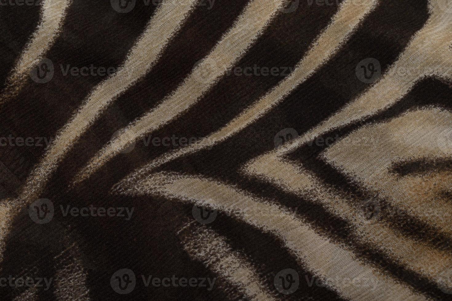 Cloth with a print of tiger stripes close-up. Drawing on the fabric of a tiger skin. photo