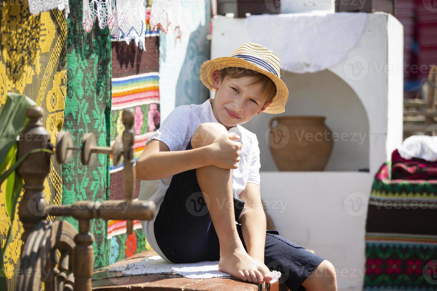 Belarusian or Ukrainian boy in a straw hat against the background of the stove. Country child. photo