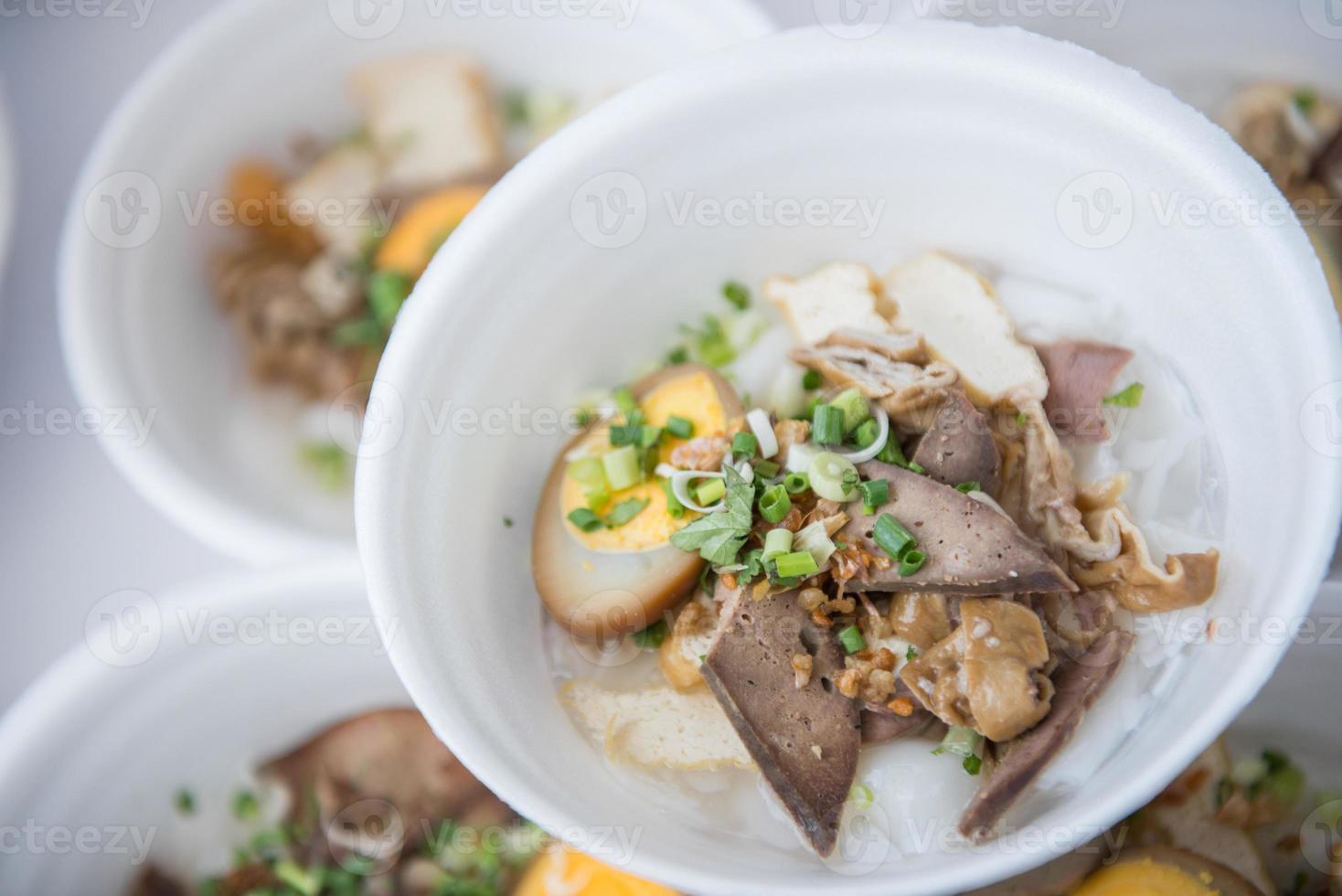 Rice noodle rolls in crunchy pork soup in foam dish photo