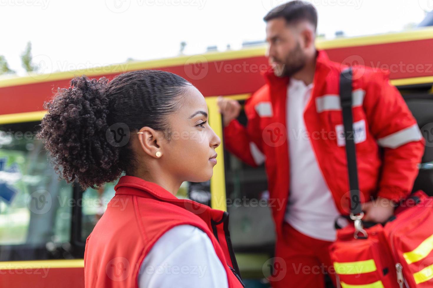 Paramedic nurse and emergency doctor at ambulance with kit. a paramedic, standing at the rear of an ambulance, by the open doors. photo