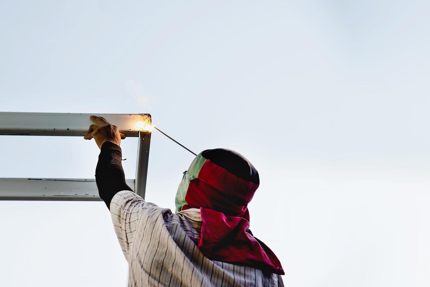 el hombre de la construcción está soldando la estructura del techo de acero, las personas que trabajan en el concepto del sitio de construcción foto