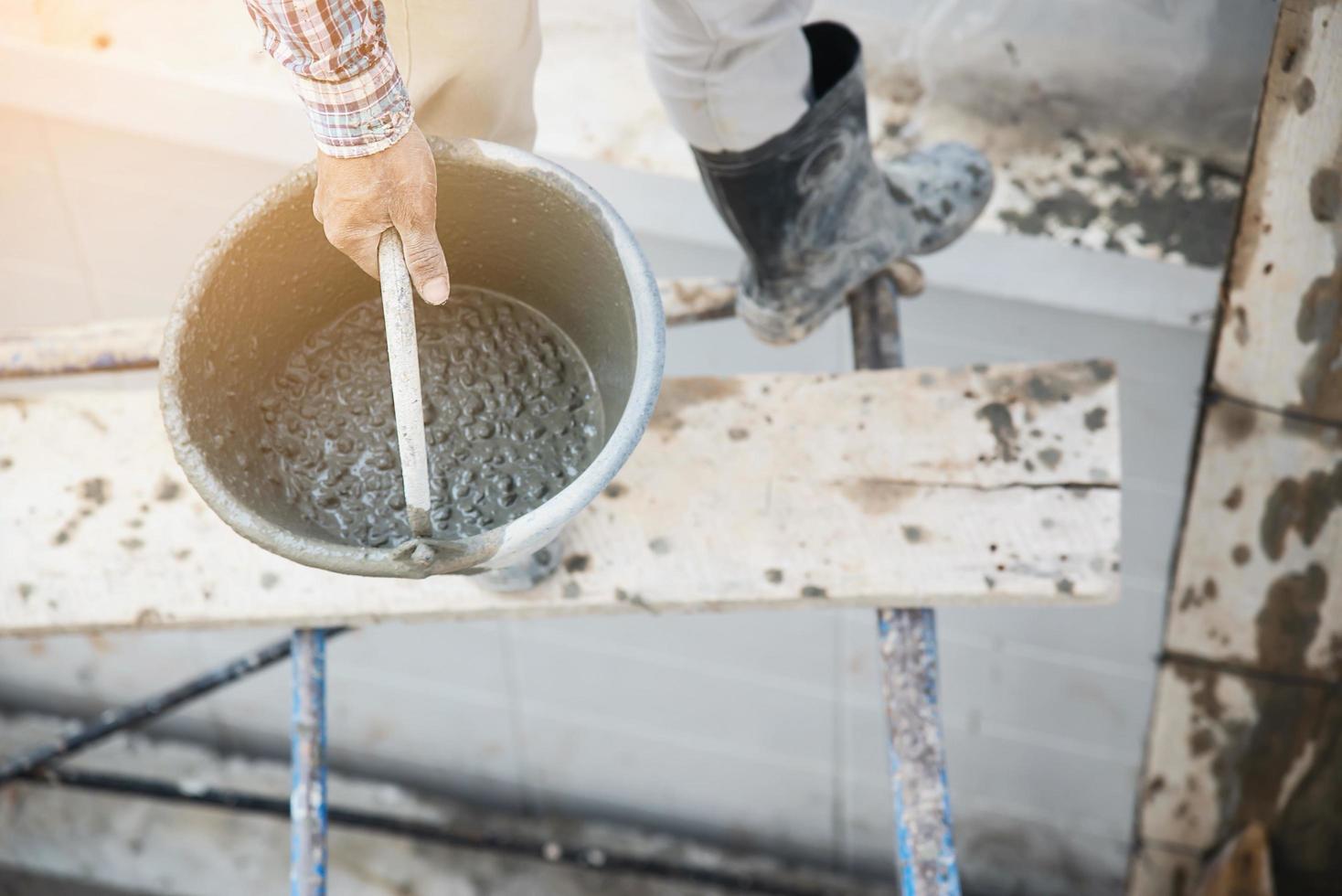 builder contractor man job holding mix fresh concrete in industry work project, prepare to pour wet liquid material into the form in construction site as professional employment photo