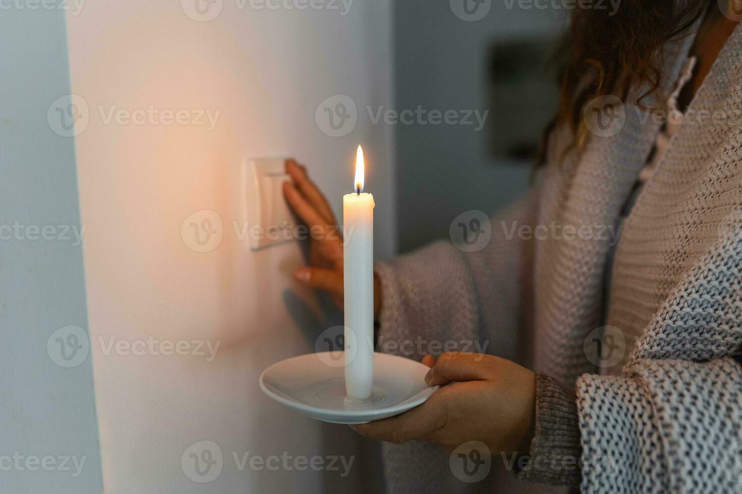 Energy crisis. Hand in complete darkness holding a candle trying to turn on light during a power outage. Blackout concept. photo