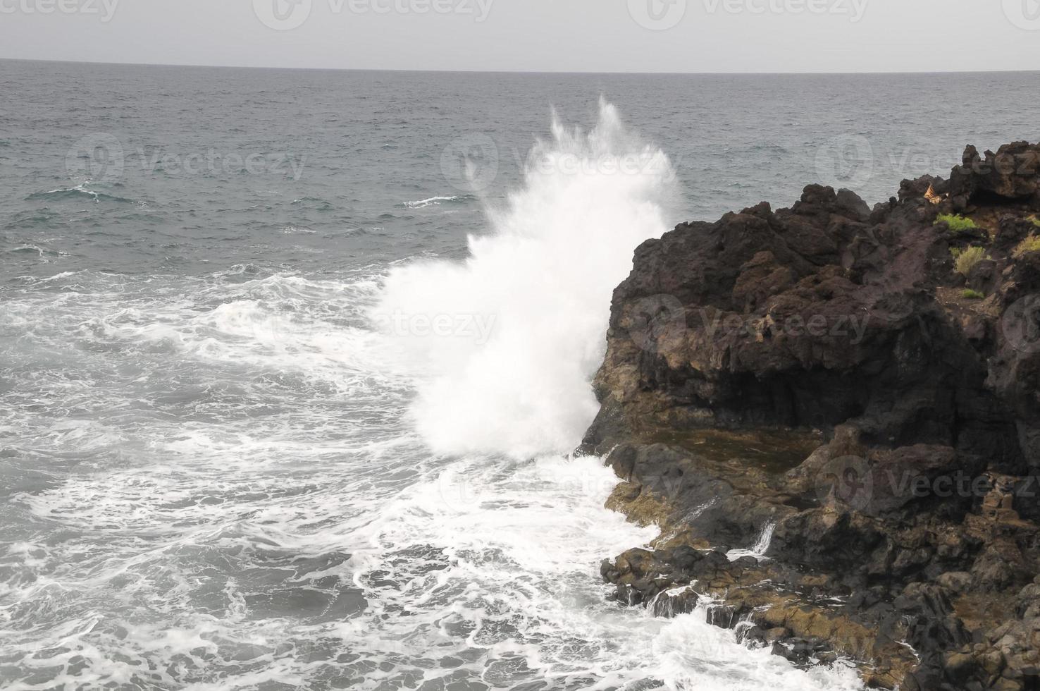 enorme mar olas estrellarse en el rocoso apuntalar foto