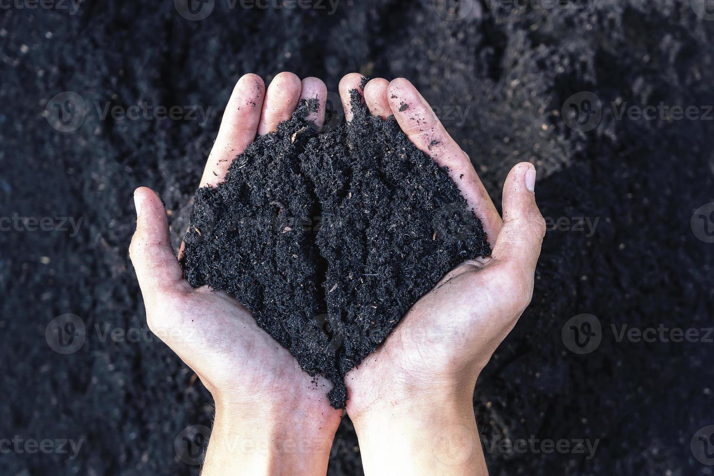 Hands holding abundance soil for agriculture or preparing to plant  Testing soil samples on hands with soil ground background. Dirt quality and farming concept. Selective focus on black soil in front photo