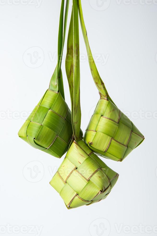 Ketupat lebaran is a typical Indonesian food during the festive season of Ketupat, Eid al Fitr, Eid al Adha, natural rice wrap made from young coconut leaves on a white background, empty space photo