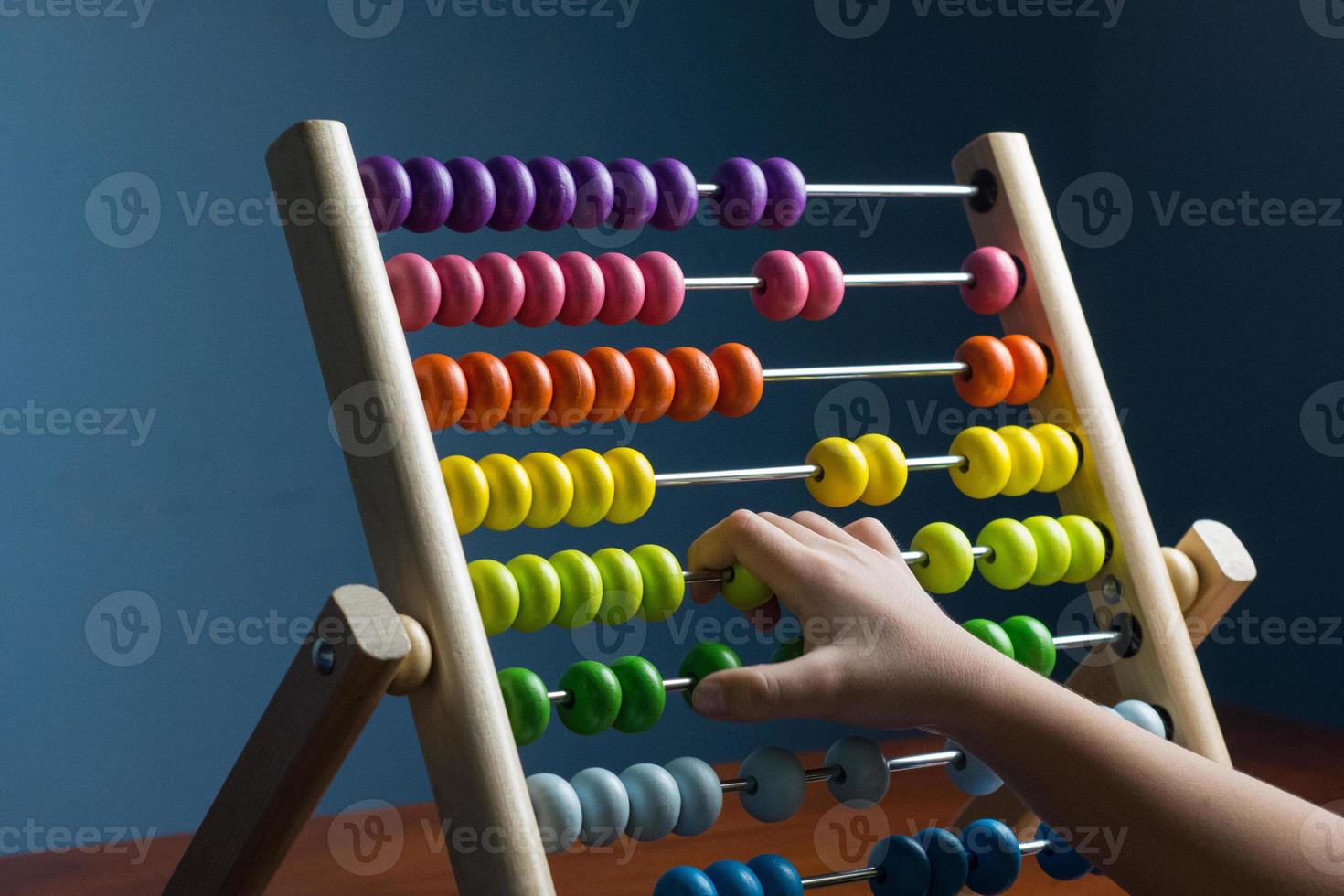 Abacus with colorful beads on blue background, close up, Counts kids learning, kids math class concept, with counting child's hands photo