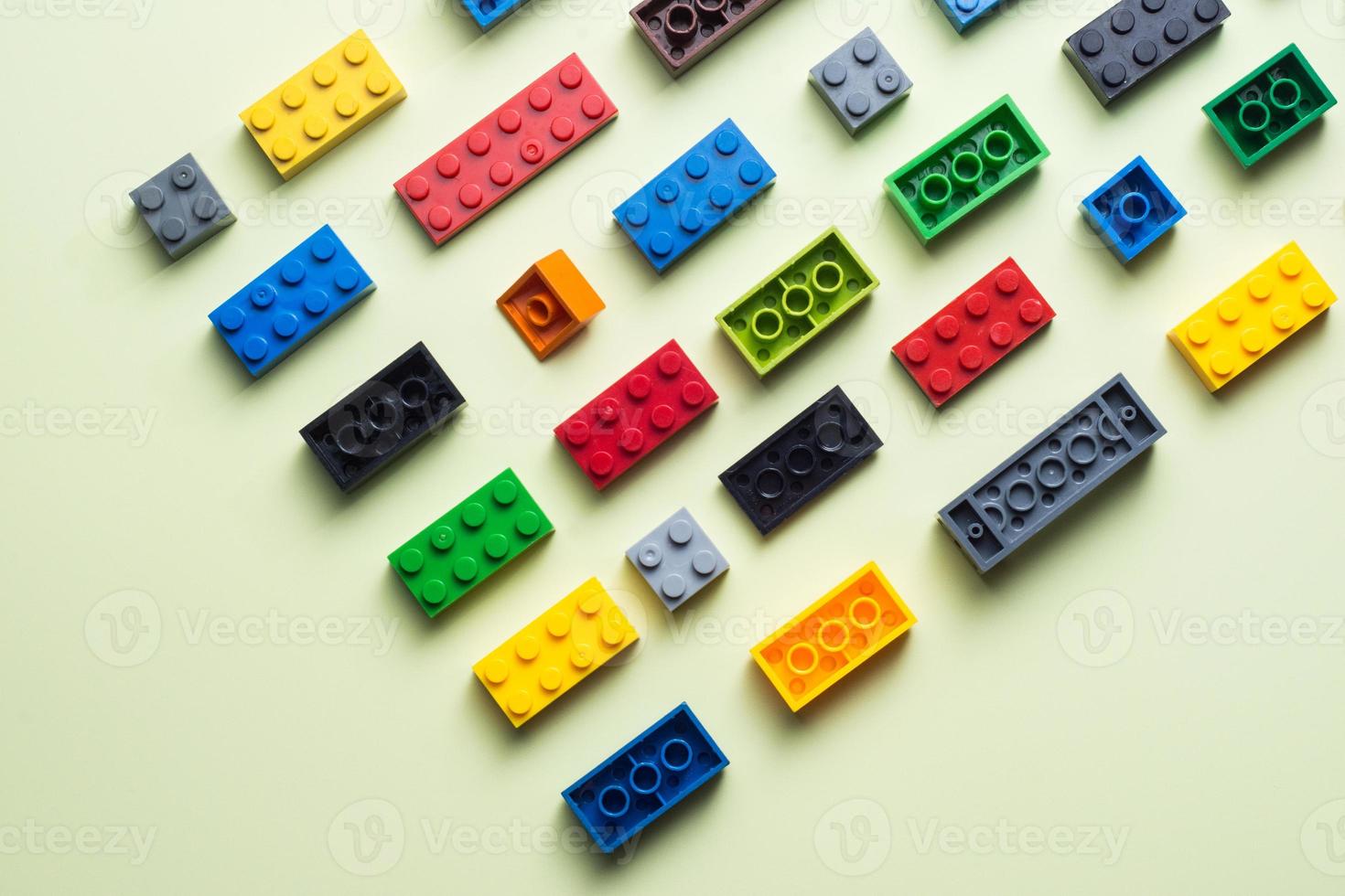 various colorful plastic toy bricks stackable blocks on yellow panoramic background, childhood education construction concept, photo