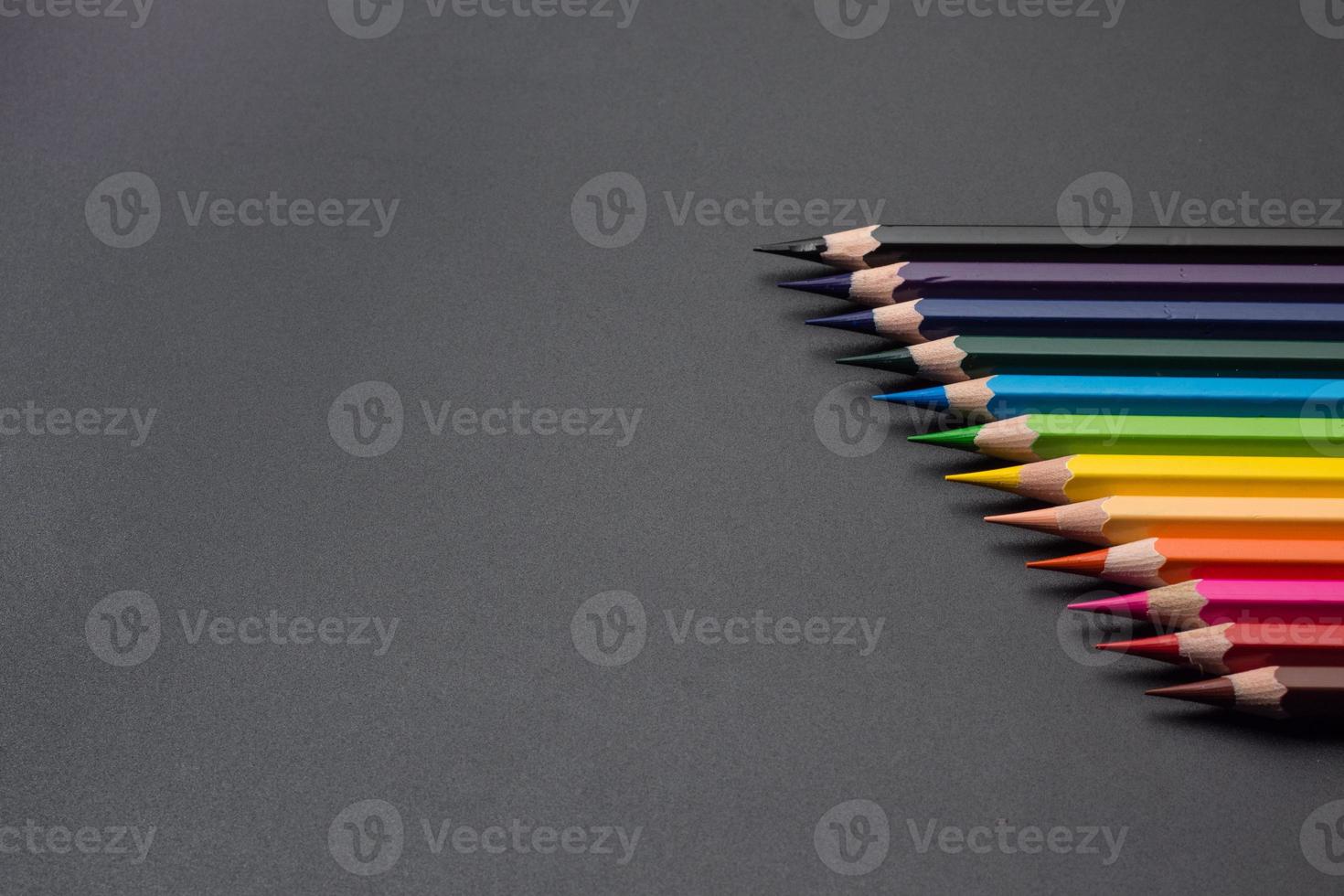 Set of colored pencils, row of wooden colored pencils on black background. colored pencils for drawing. pencils arranged in rainbow colors, colorful, copy space. photo