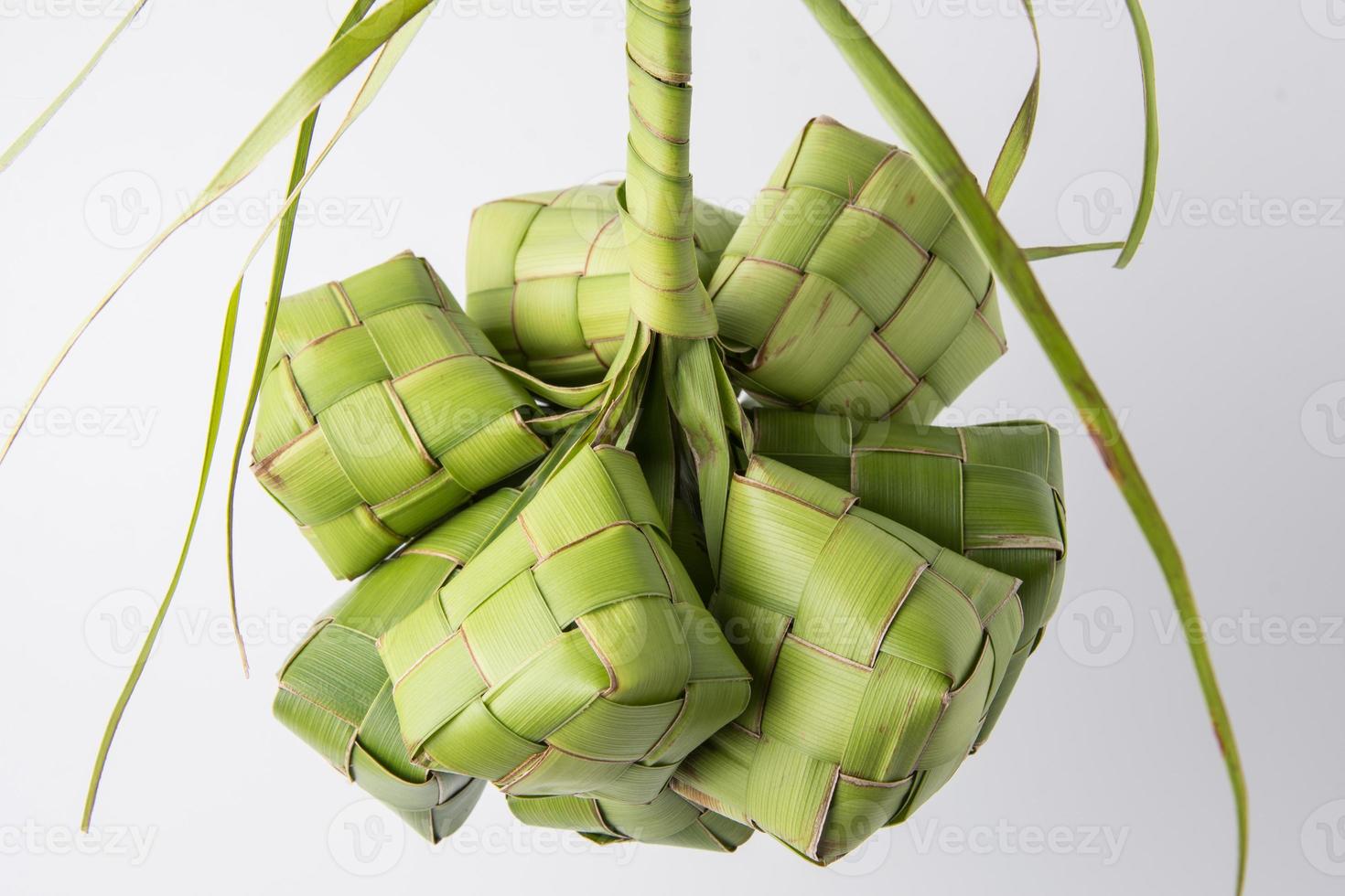 Ketupat lebaran is a typical Indonesian food during the festive season of Ketupat, Eid al Fitr, Eid al Adha, natural rice wrap made from young coconut leaves on a white background, empty space photo