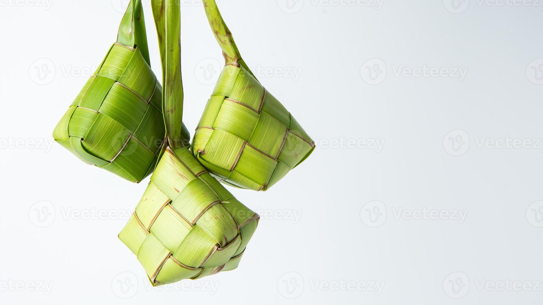 Ketupat lebaran is a typical Indonesian food during the festive season of Ketupat, Eid al Fitr, Eid al Adha, natural rice wrap made from young coconut leaves on a white background, empty space photo