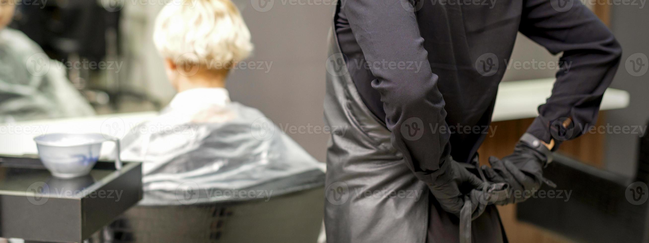 Hairdresser ties up black apron photo