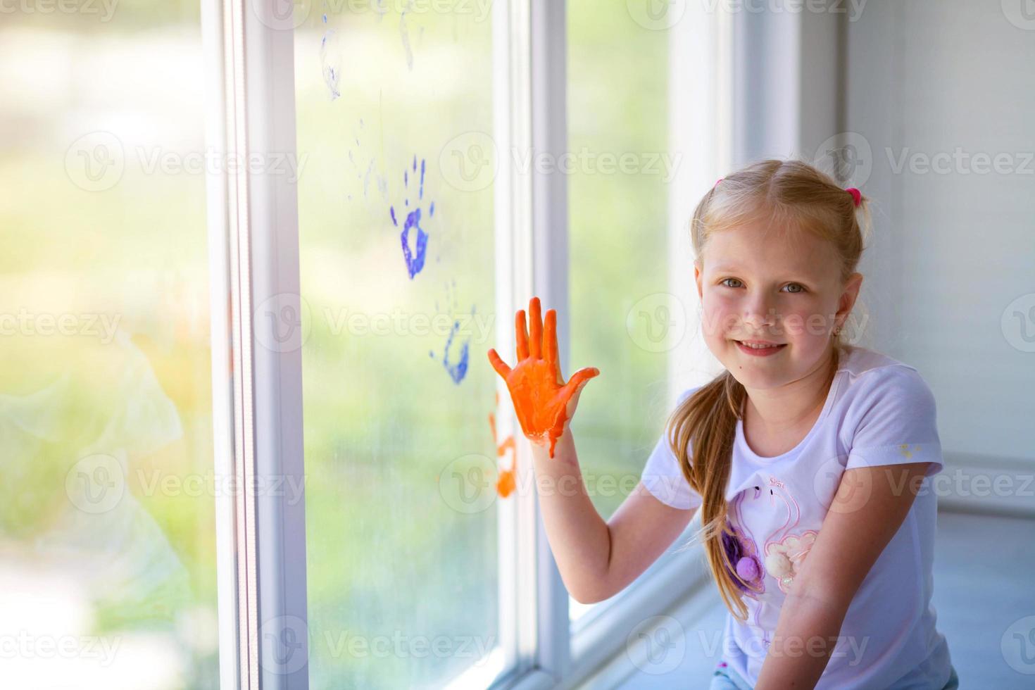 Children girl draw with palms on the window. Painted hands leave a mark on the glass. Quarantine. Stay home. photo