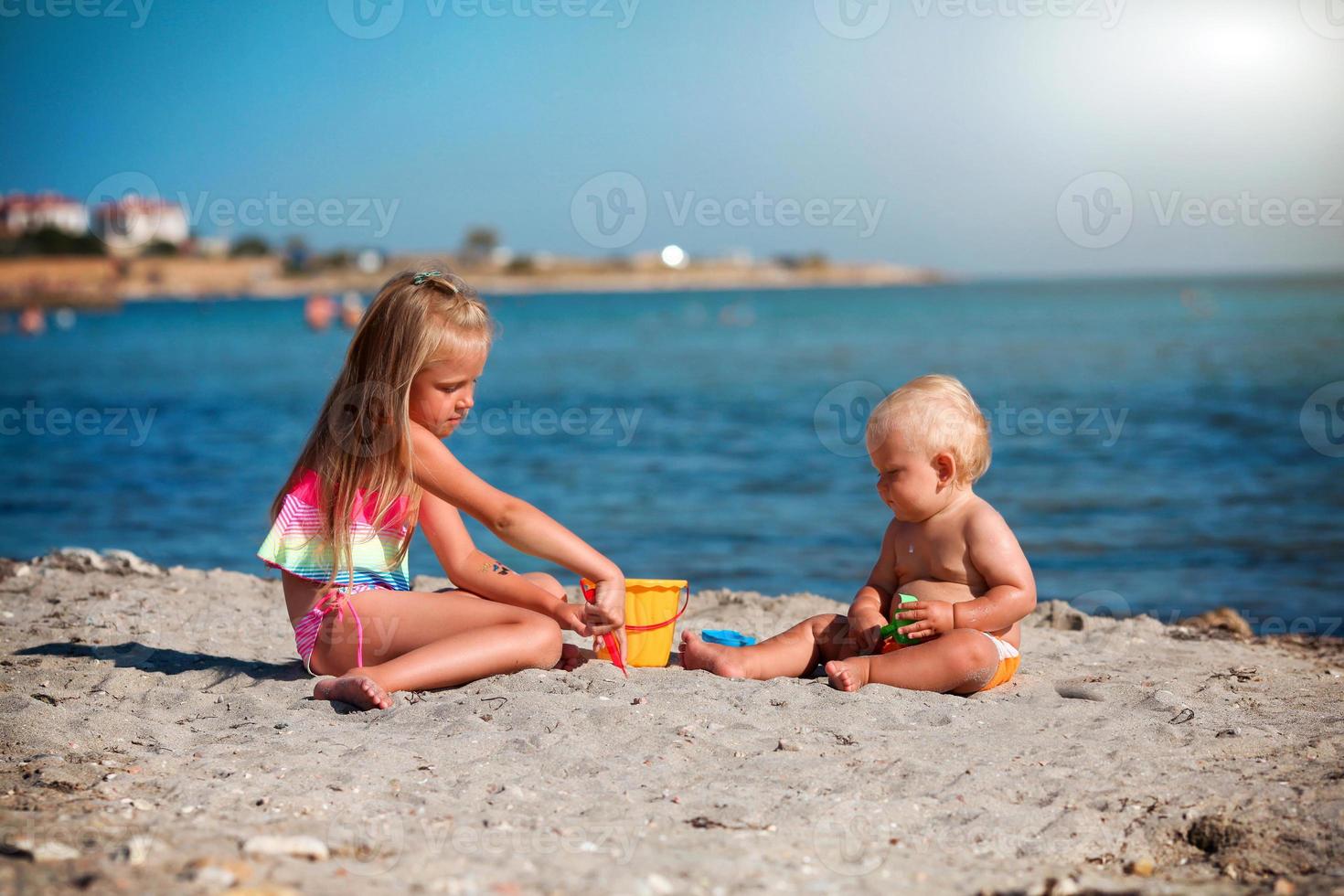 niños jugar en el playa. verano agua divertido para el familia. chico y niña con juguete cubos y un pala en el costa. foto