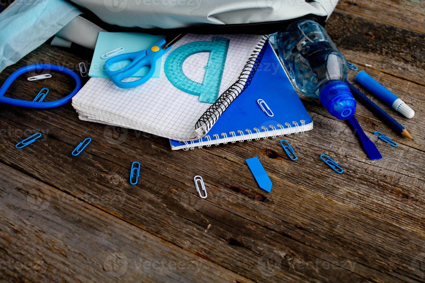 Backpack with school supplies and  on wooden background. View from above.  Back to the school concept. photo