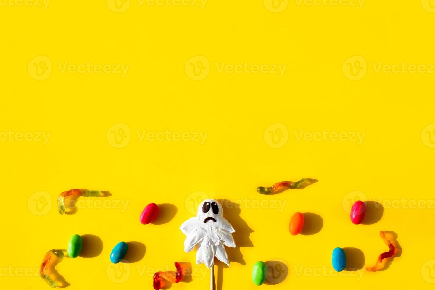 Top view of Halloween candy ghost, jelly worms  on yellow background . photo