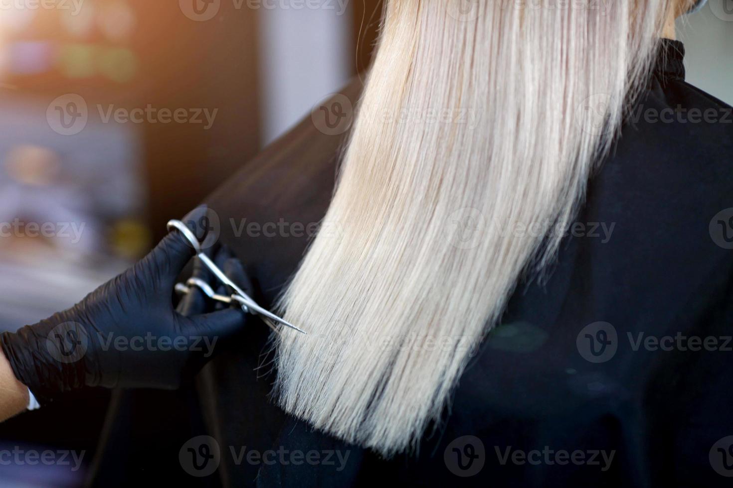 A hairdresser in rubber gloves holds a pair of scissors and a comb. Woman getting a new haircut. photo