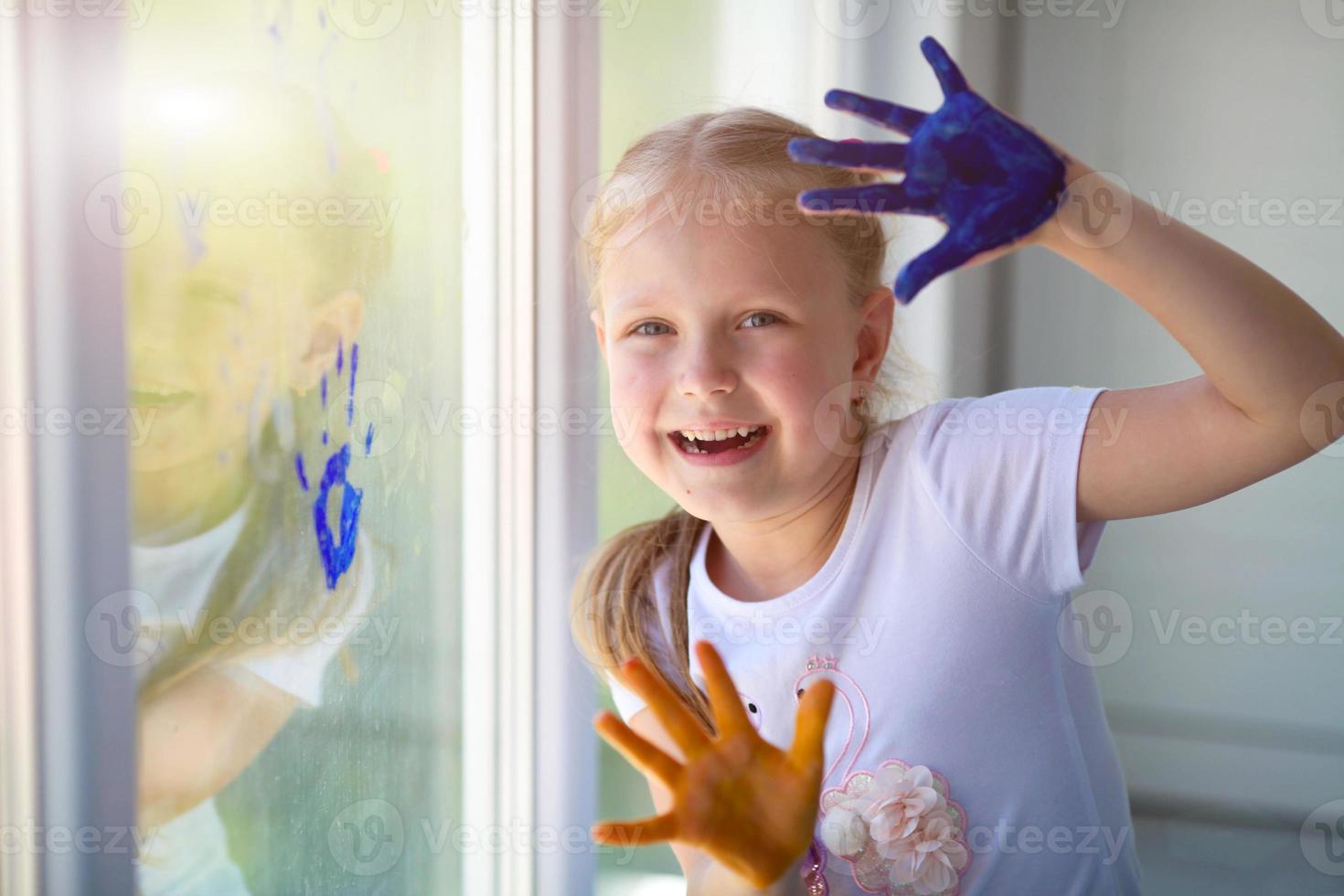 Children girl draw with palms on the window. Painted hands leave a mark on the glass. Quarantine. Stay home. photo