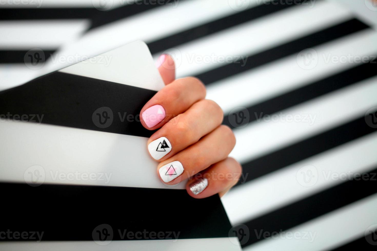 Female hands with a beautiful manicure on a striped background. photo