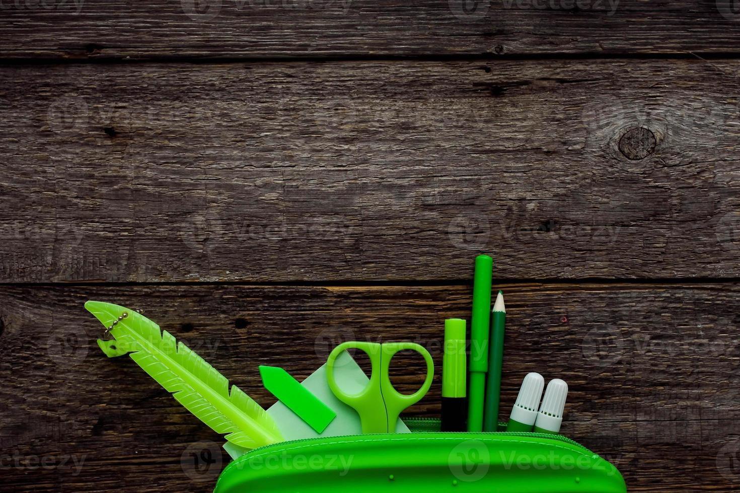 Pencil case and school supplies on a wood background. Stationery green. Back to school concept. photo