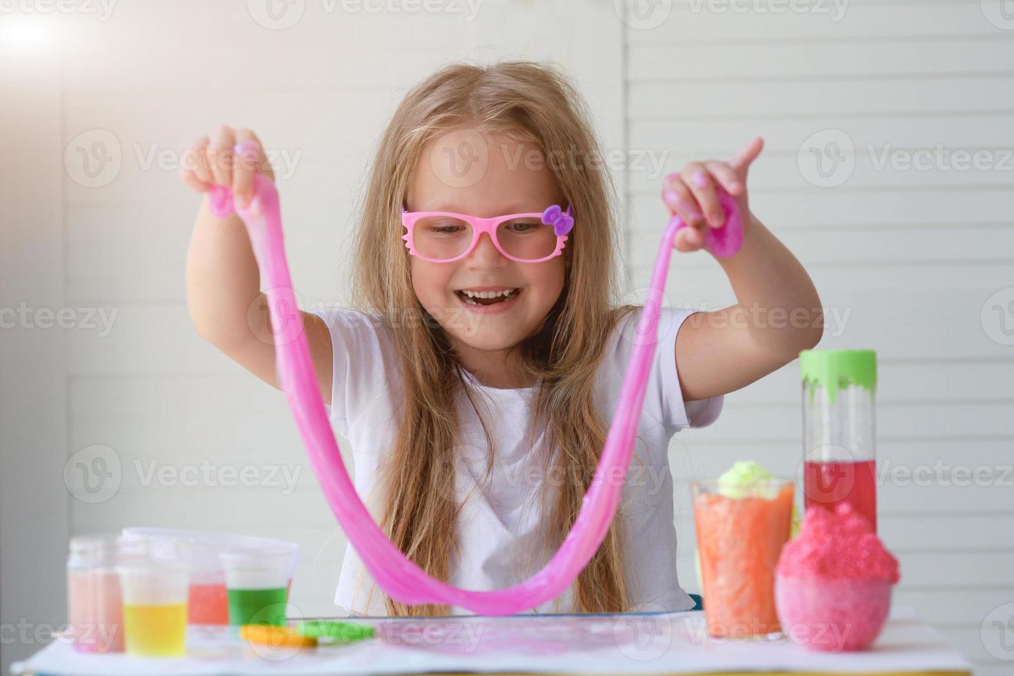 A little girl in pink glasses pulls the mucus up. photo