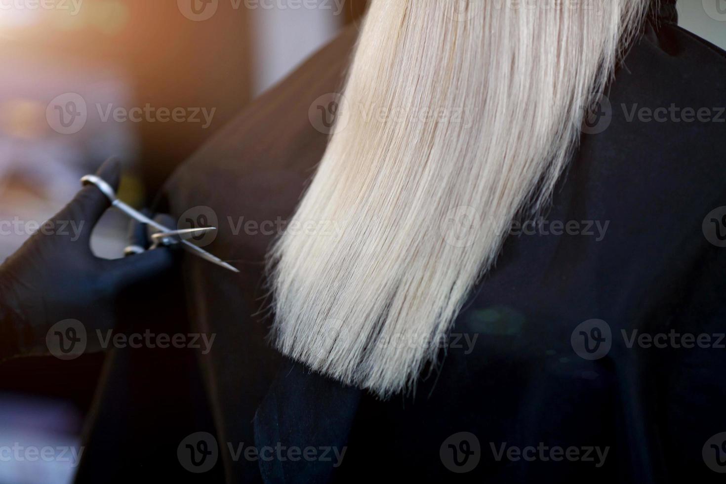 A hairdresser in rubber gloves holds a pair of scissors and a comb. Woman getting a new haircut. photo