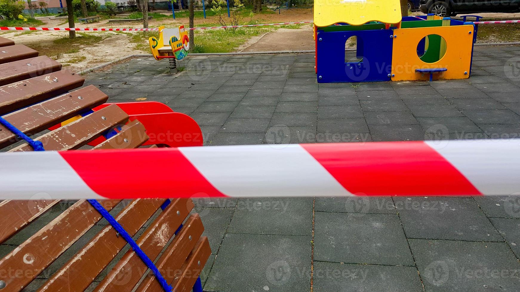 Children is playground closed and wrapped in alarm caution tape for global coronavirus quarantine.No children on playgrounds. photo