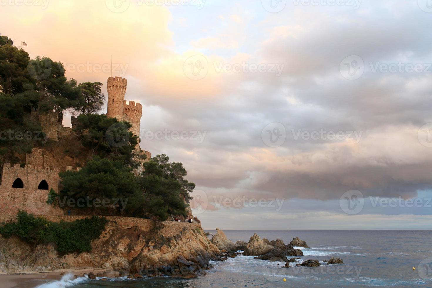 ancient fortress with towers on a rocky seashore, low clouds, rocks, seascape photo