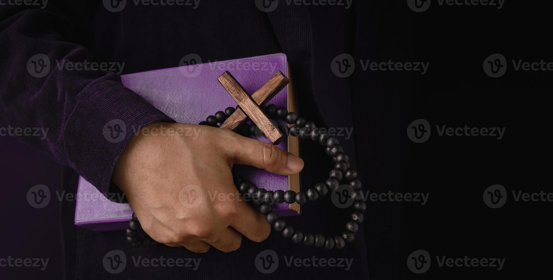 Spirituality, Religion and Hope Concept. Person Holding a Holy Bible, Bead and Cross. Symbol of Humility, Supplication, Believe and Faith for Christian People. Dark Tone, Close-Up and Side View photo