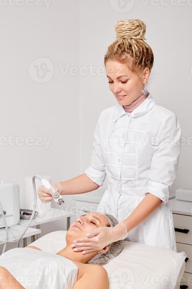 cosmetóloga hace peeling epidérmico de suero de oxígeno líquido de gas facial para el rejuvenecimiento de la cara de la mujer foto