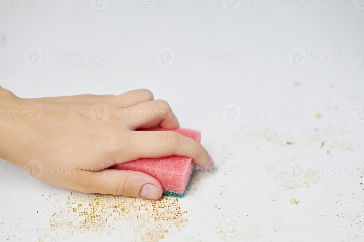 Sponge in woman hand removes dirt, bread crumbs and leftovers. Cleaning kitchen table. Household chores photo