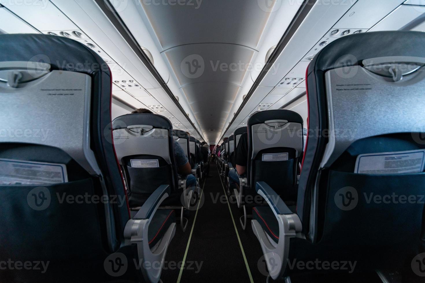 Airplane cabin seats with passengers. Economy class of new cheapest low-cost airlines without delay or cancellation of flight. Travel trip to another country. photo
